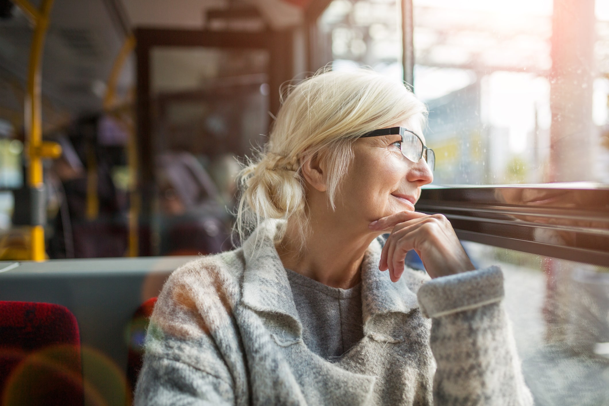 Senior Woman Looking Through Window While Traveling In Bus